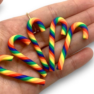 May include: Five rainbow candy cane ornaments made of polymer clay. Each cane is striped with red, orange, yellow, green, blue, and purple.