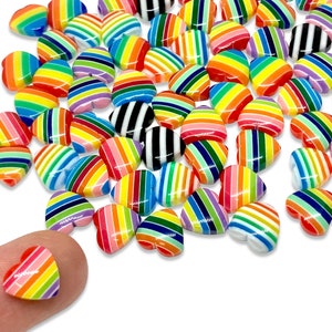 May include: A large group of colorful rainbow striped heart-shaped beads. The beads are made of plastic and have a glossy finish.