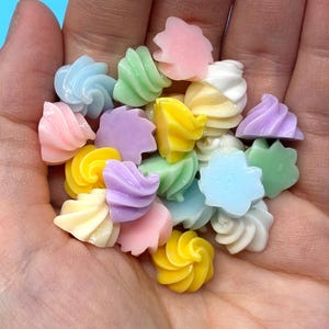 May include: A collection of small, swirl-shaped cabochons in pastel colors including pink, yellow, blue, green, purple, and white. Each piece features a spiraled, icing-like texture with a smooth, glossy finish, designed for crafting and decorative use.