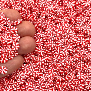 May include: A large pile of red and white candy cane sprinkles. The sprinkles are in the shape of a candy cane and are perfect for decorating cakes, cupcakes, and other desserts.