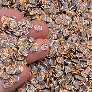 May include: A large collection of small, flat, circular clay slices featuring a stylized orange, white, and black clownfish pattern. Each individual piece has a distinct fish shape with defined stripes and a small hole for threading or crafting.
