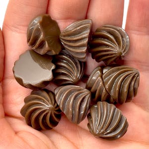 May include: A collection of brown swirl-shaped buttons. The buttons are made of plastic and have a glossy finish.