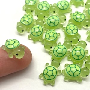 May include: A collection of small, green plastic turtle figurines. The turtles have a light green shell with a darker green outline. The turtles are about 1 inch in size.