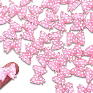 May include: A large group of pink and white polka dot bows. The bows are made of a shiny, translucent material.