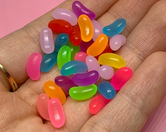 May include: A collection of colorful jelly bean shaped candies in various shades of pink, purple, blue, green, yellow, orange, and red.