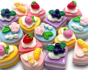 May include: Assortment of colorful miniature cakes with various toppings, including strawberries, blueberries, flowers, and corn. The cakes are made of polymer clay and are perfect for crafting and decorating.