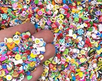 May include: A handful of colorful polymer clay embellishments in various shapes, including fruits, animals, and sweets. The assortment features a panda, a strawberry, a slice of orange, and a smiley face. The background is filled with similar miniature decorations.