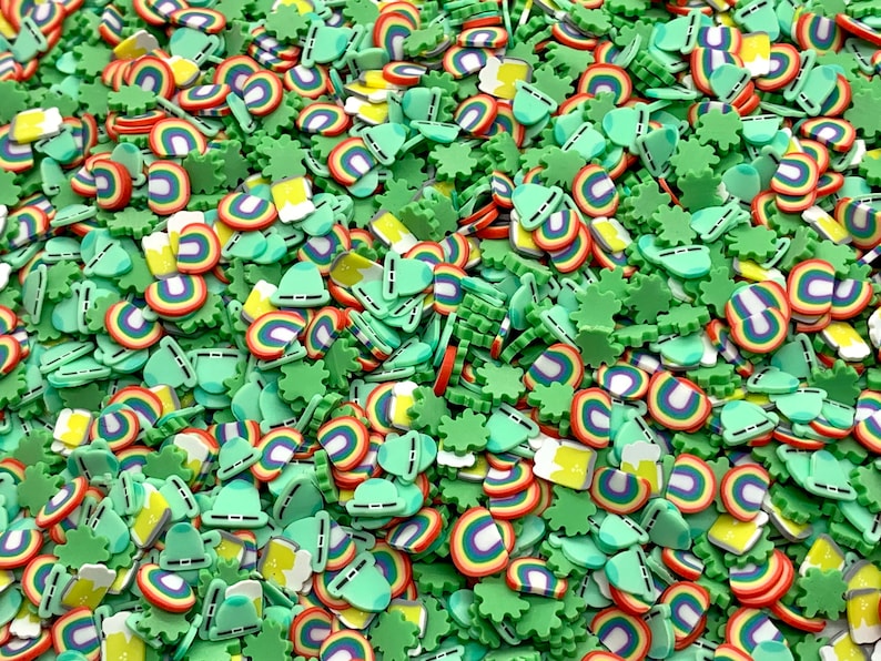 May include: A mix of green, yellow, red, and blue sprinkles in the shape of shamrocks, rainbows, beer mugs, and hats.