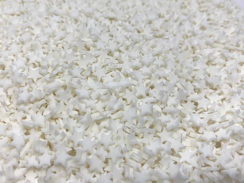 May include: A close-up image of a large quantity of white star-shaped sprinkles. The sprinkles are small and perfect for decorating cakes, cupcakes, and other desserts.
