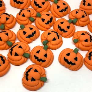 May include: A collection of 20 orange pumpkin-shaped Halloween decorations with black eyes, noses, and mouths. Each pumpkin has a green stem.