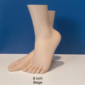 May include: Beige mannequin feet, 8 inches tall. The feet are posed as if walking, with one foot in front of the other.