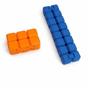 May include: Two fidget toys are shown. One is orange and the other is blue. Each toy is made of connected, square blocks. The orange toy is in a 2x3 configuration, while the blue toy is a long, straight line of blocks.
