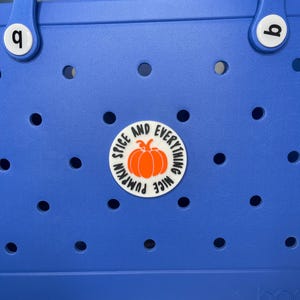 May include: Blue tote bag with a white circle sticker that says "Nice Pumpkin Spice and Everything". The sticker has an orange pumpkin on it.