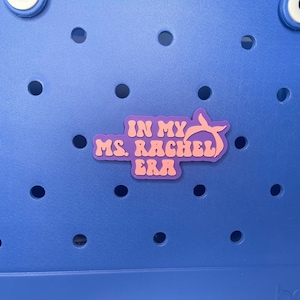 May include: A purple and pink sticker with the text "In My Ms. Rachel Era" on a blue background.