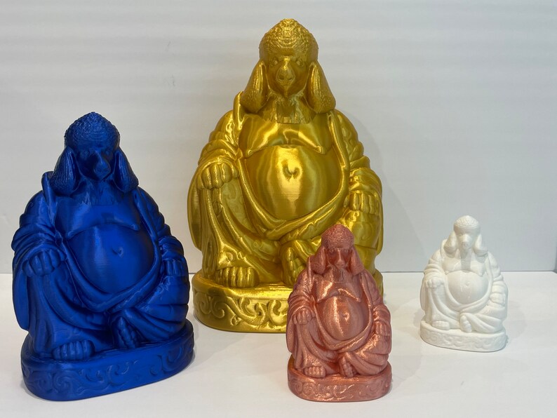May include: Four Buddha statues in varying sizes and colors. The largest is gold, the next is blue, followed by a copper-colored statue, and the smallest is white. All statues are seated with a serene expression and detailed robes.