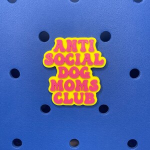 May include: A yellow and pink 3D sticker with the text "Anti Social Dog Moms Club" in a retro font.