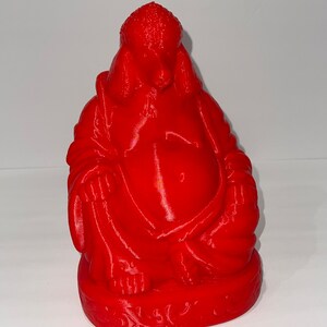 May include: A vibrant red Buddha statue, featuring a seated figure with a large belly and serene expression. The statue is detailed with folds in the robes and a textured head. The base has an ornate design.