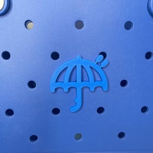 May include: A blue tote bag with a blue umbrella logo. The bag has a textured surface with small holes.