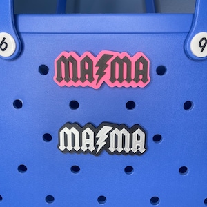 May include: Two "Mama"  charms with a lightning bolt design. The top charm is black on pink and the bottom charm is silver on black.