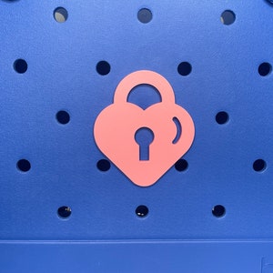May include: A blue tote bag with a pink heart-shaped padlock design.