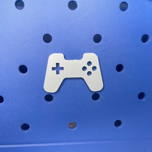May include: A white plastic game controller icon on a blue background with a pattern of small holes.