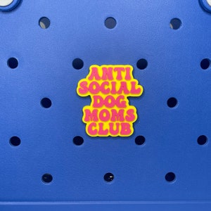 May include: A yellow and pink sticker with the text "Anti Social Dog Moms Club" on a blue background.