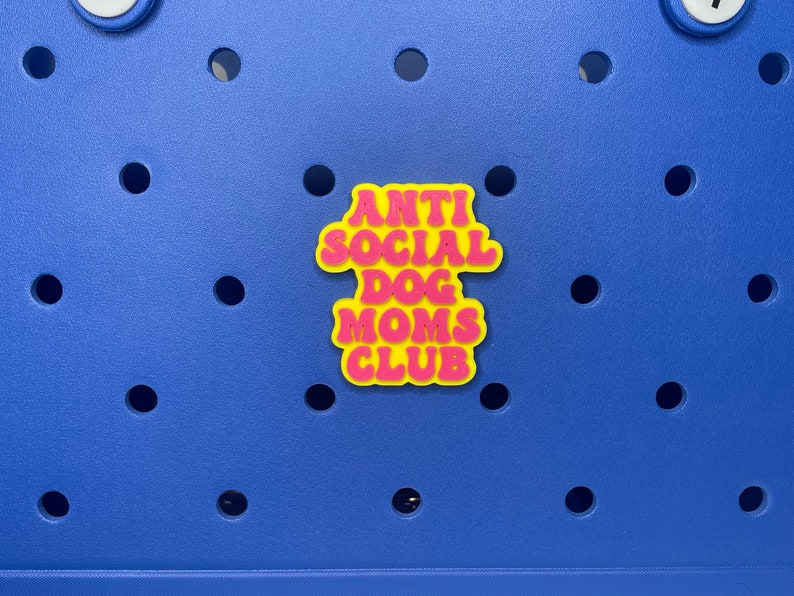 May include: A yellow and pink sticker with the text "Anti Social Dog Moms Club" on a blue background.