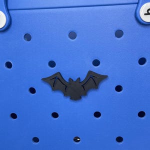 May include: A blue tote bag with a black bat cutout. The bag has a  perforated design.