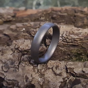 Könnte beinhalten: Ein schlichter, silberfarbener Ehering mit glatter, matter Oberfläche.