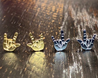 May include: Four pairs of gold and silver earrings shaped like the American Sign Language symbol for "I love you".