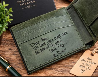 May include: A dark green leather bifold wallet featuring an interior engraving that reads: Dear Ava, We love you and are so proud of you! Love Mom & Dad. The wallet includes multiple card slots and is presented with a tan paper tag that reads: More than a Wallet A Story With You.