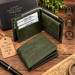 Puede incluir: Una cartera bifold de cuero verde oscuro con acabado texturizado, que cuenta con múltiples ranuras interiores para tarjetas con insertos blancos, un monedero y un compartimento para billetes. Se muestra junto a una caja de regalo negra.