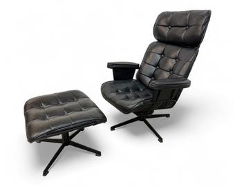 May include: Black leather armchair and ottoman set. The chair has a high back with a headrest, armrests, and a button-tufted design. The ottoman is square and also features a button-tufted design. Both pieces have black metal bases.
