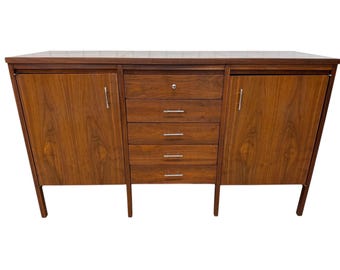 May include: A mid-century modern wooden cabinet with a dark brown finish. The cabinet has two doors, four drawers, and a top surface. The doors and drawers have silver handles. The cabinet is supported by four legs.