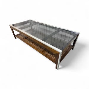 May include: Rectangular coffee table with a glass top and a lower shelf. The frame is a combination of wood and silver metal. The lower shelf has a woven cane design. The table is a mid-century modern style.