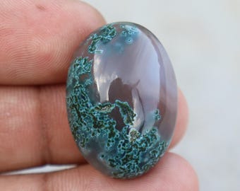 Può includere: Una gemma di forma ovale con una superficie lucida. La pietra presenta un mix di colori, tra cui un bordeaux intenso e verde acqua. Il verde acqua ha un aspetto muschioso e strutturato, mentre il bordeaux è liscio e riflettente.