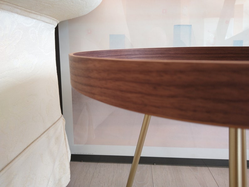 K&ouml;nnte beinhalten: Ein runder Holztisch mit einer dunkelbraunen Holzplatte und goldenen Metallbeinen. Der Tisch steht auf einem hellen Holzboden.