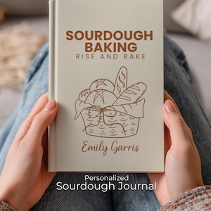 May include: A beige journal titled "Sourdough Baking Rise and Bake" with a basket of bread illustration. The journal is personalized with the name "Emily Garris" and the text "Personalized Sourdough Journal" at the bottom.