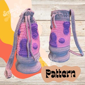 May include: A crocheted drawstring bag with a pink and purple colour scheme. The bag has a long strap and a round bottom. The bag is made with a textured stitch and has a pattern of circles and ovals.