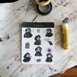 May include: A sheet of stickers featuring a black and white illustration of a bird wearing a plague doctor mask. The stickers include various designs, such as the bird holding a vial, a skull, a tombstone, a mouse, and a raven. The text "Plague Birb" and "Nevermore" are included on the sheet.