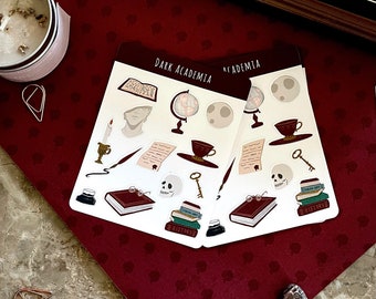 May include: Two sheets of stickers with a dark academia theme. The stickers feature images of books, a globe, a quill, a skull, a cup of tea, a key, and the words "Dark Academia" and "Academia".