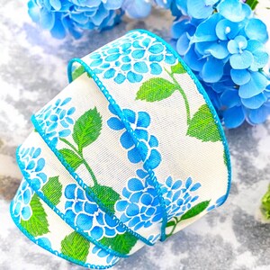 May include: White ribbon with a blue and green hydrangea print. The ribbon is curled and has a turquoise edge.