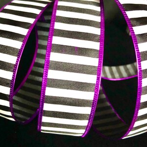 May include: Black and white striped ribbon with a purple edge. The ribbon is folded and twisted.