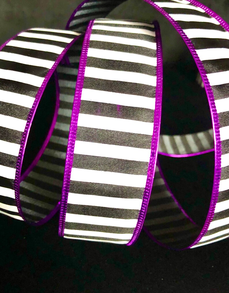 May include: Black and white striped ribbon with a purple edge. The ribbon is folded and twisted.