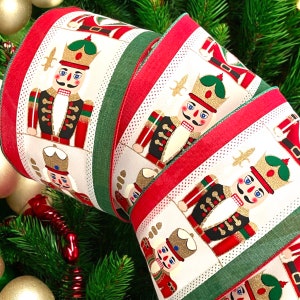 May include: Red, green and white ribbon with a repeating pattern of nutcracker figures. The nutcrackers are wearing red, gold and black uniforms. The ribbon is ideal for decorating Christmas gifts or wreaths.