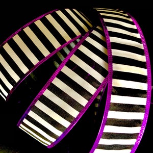 May include: Black and white striped ribbon with a purple edge. The ribbon is curled and folded, showing the pattern.