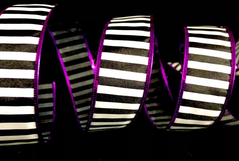 May include: Black and white striped ribbon with a purple edge. The ribbon is curled and twisted.