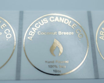 May include: Three gold foil labels with the text "ABACUS CANDLE CO." and "Coconut Breeze" in a circle. The labels also include the text "Hand Poured 100% Soy 10oz".