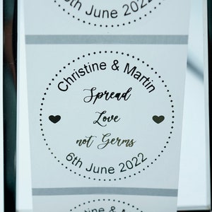 Puede incluir: Una hoja de pegatinas blancas con texto negro y corazones. Las pegatinas dicen "Christine & Martin Spread Love not Germs 6th June 2022".