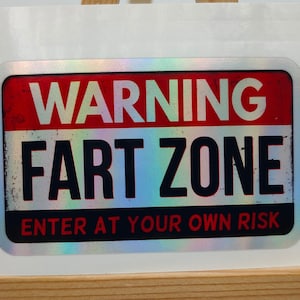 Może przedstawiać: Srebrna naklejka z czerwono-białym znakiem ostrzegawczym z napisem "WARNING FART ZONE ENTER AT YOUR OWN RISK".